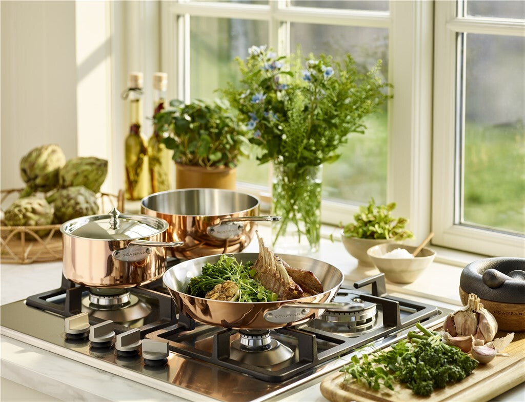 SCANPAN Maitre D' copper cookware in use on a gas hob in a bright kitchen