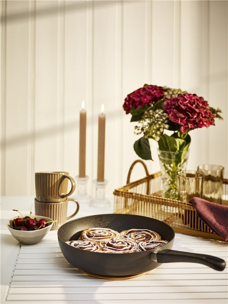 SCANPAN Classic Induction sauteerpan met een bereid gerecht tegen een donkere achtergrond